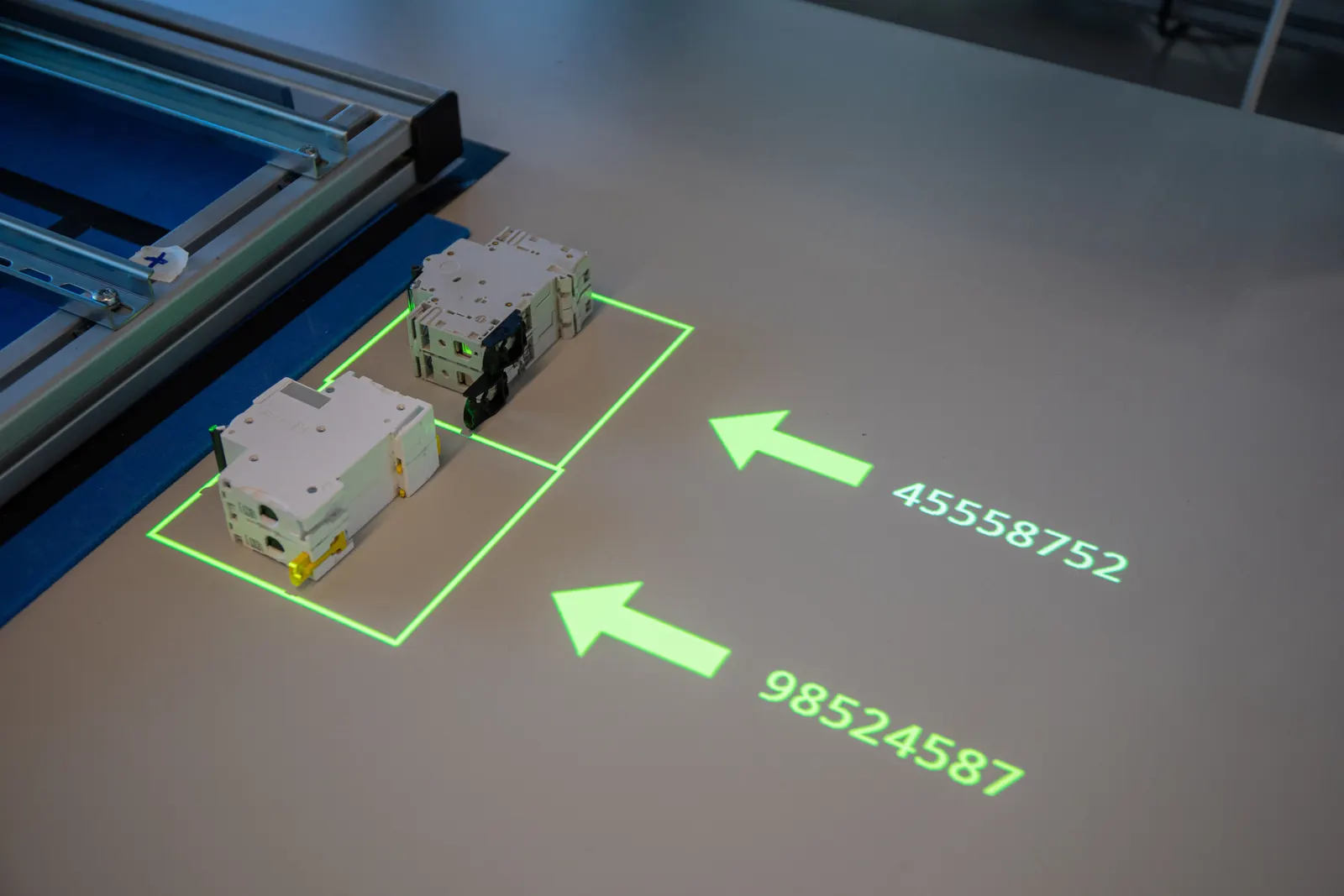 Projected arrows and part numbers on the work surface show where each component goes