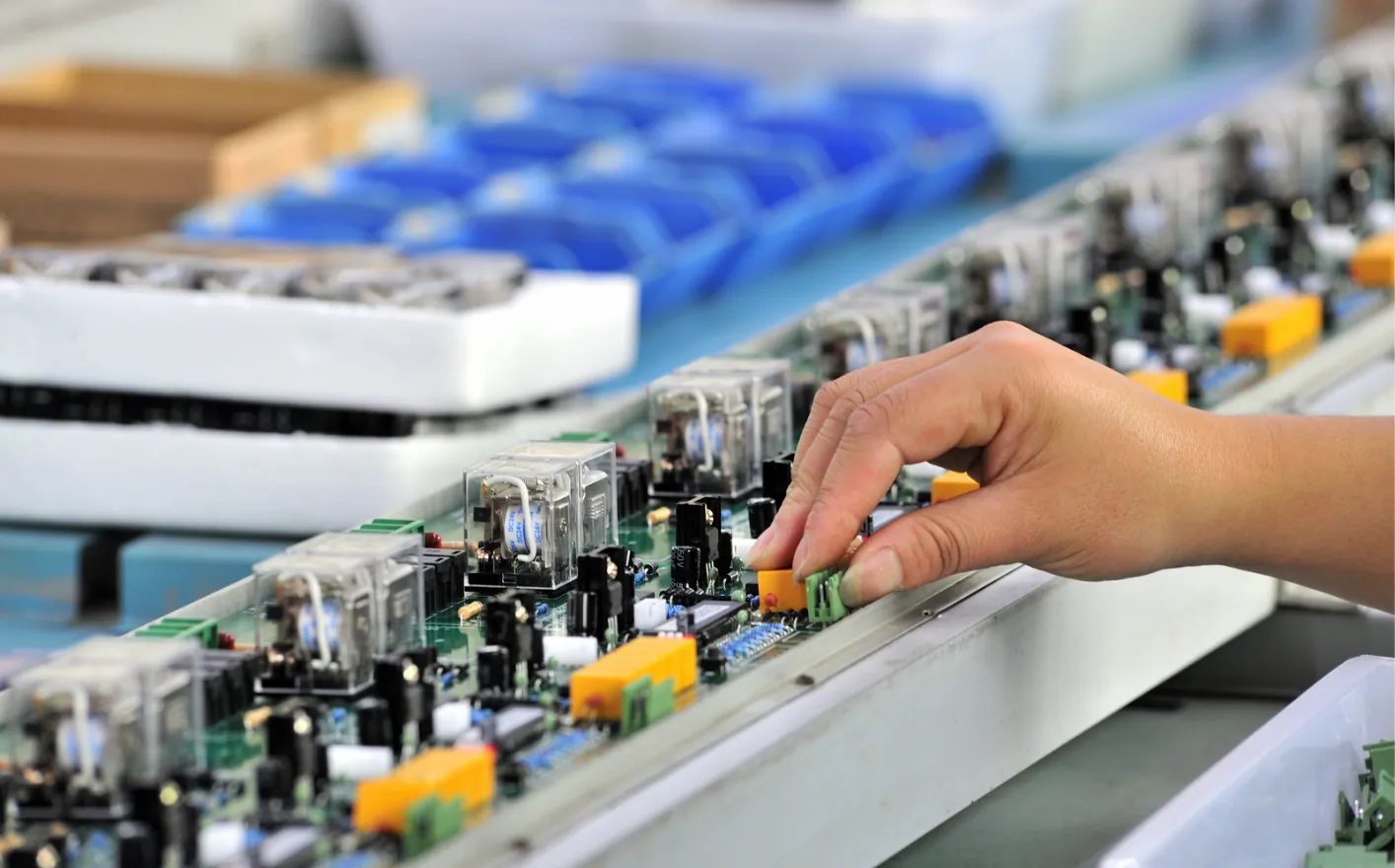 Operator placing a component on a printed circuit board in a manual electronics assembly line