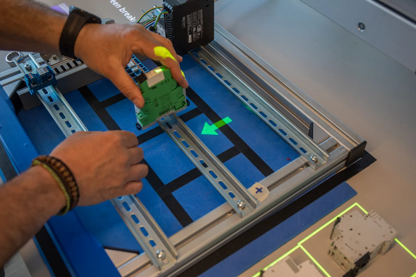 Operator mounting a component on a DIN rail while a projected arrow shows the correct position