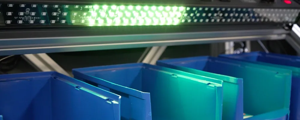DMX pick-to-light bar illuminating the correct picking bin above a row of blue bins